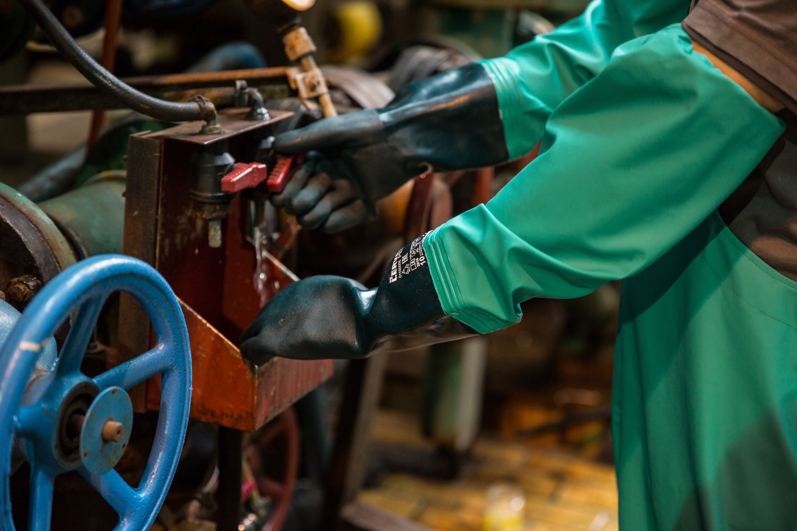 Engenheiro com EPI operando válvulas e tubulações industriais